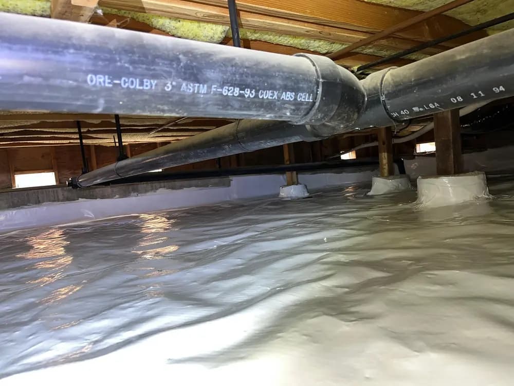 Crawl space with a continuous vapor barrier covering the ground and sealed around the pier footings.