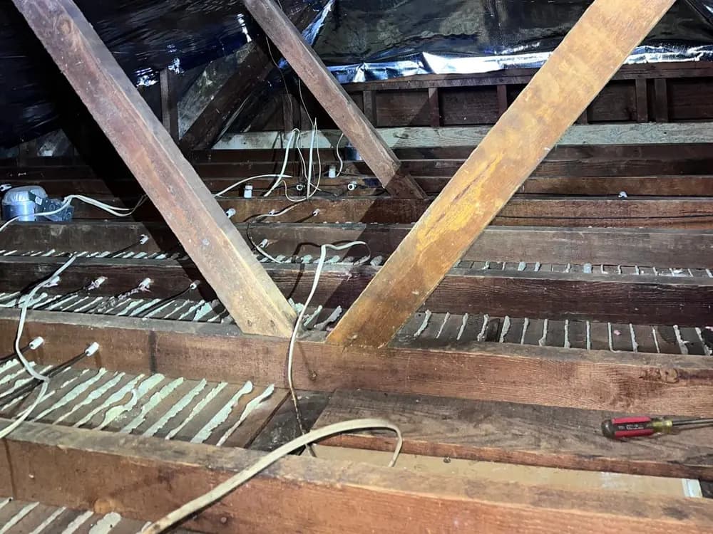Reflective radiant barrier stapled to the underside of the roof rafters, with its foil face toward the attic air space.