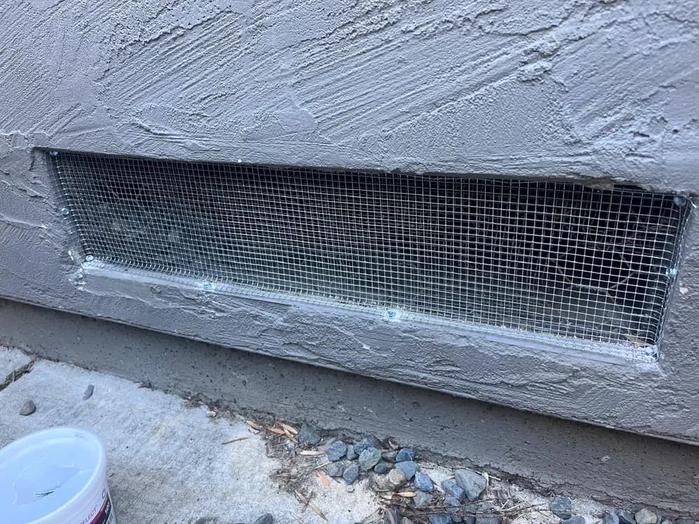 Long foundation vent fitted with galvanized mesh and sealed along its full perimeter.