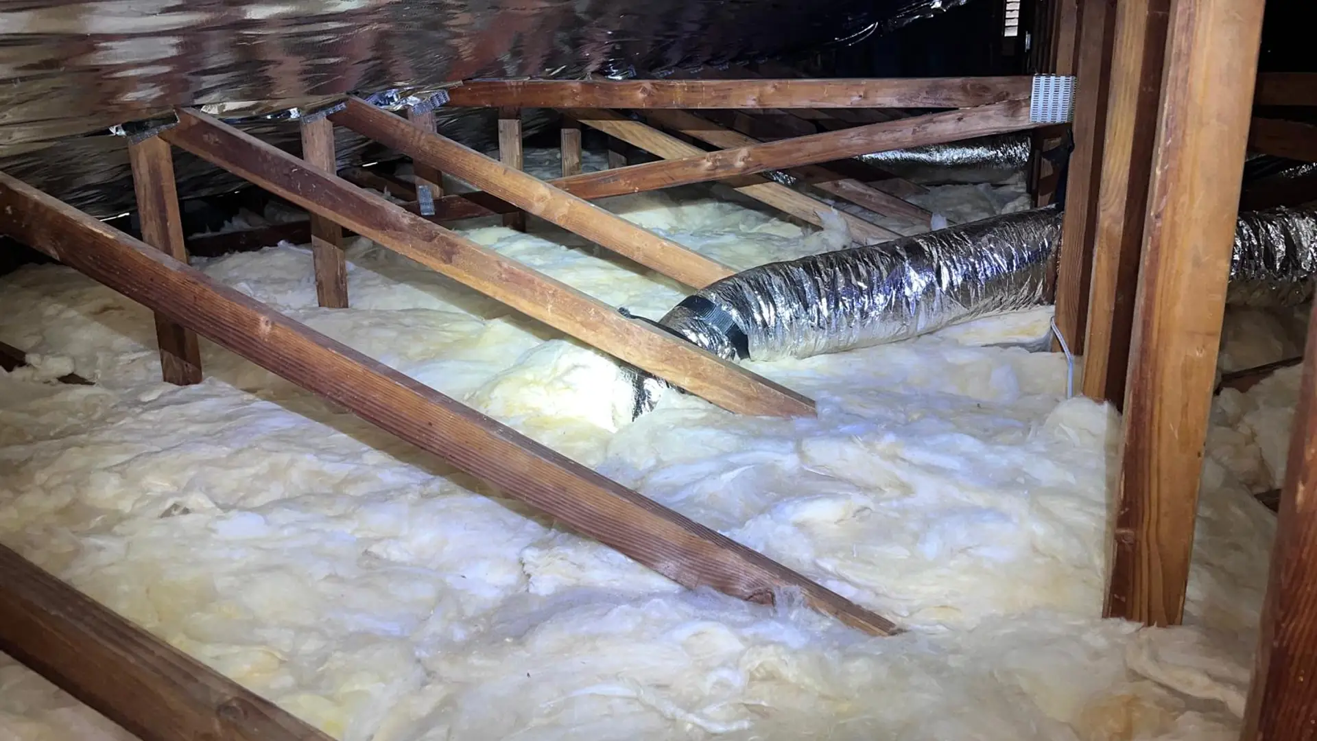 Attic floor insulated evenly between the joists, with a radiant barrier fitted along the roof line above.